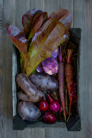 Various violet vegetables on the black wooden table, top view