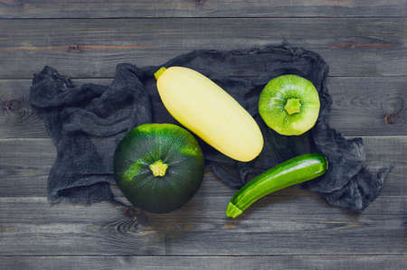 Dark composition with various zucchini and squashes on the black wooden table, top viewの写真素材