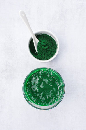Spirulina powder and smoothie on the light grey table, top view