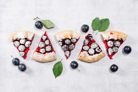 Peaces of homemade plum galette on the grey table, top viewの写真素材