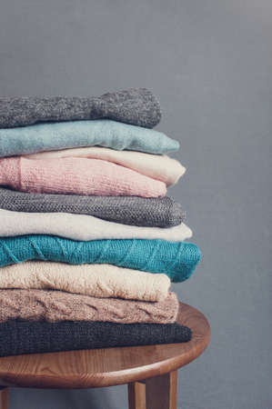 Stack of knitted clothes on the wooden table, gray backgroundの写真素材