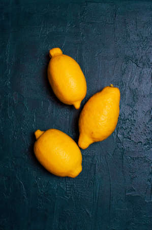 Three fresh lemons on the navy blue textured table, top viewの写真素材