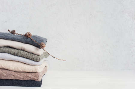 Light background with stack of knitted casual clothes various colors and textures, copy spaceの写真素材