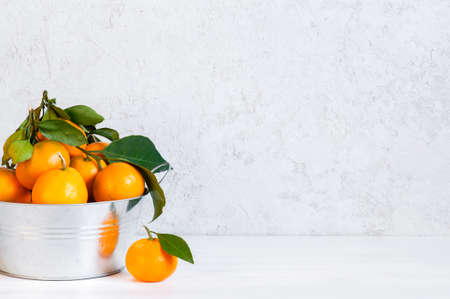 White background with fresh ripe tangerines in the metal bowl, copy spaceの写真素材
