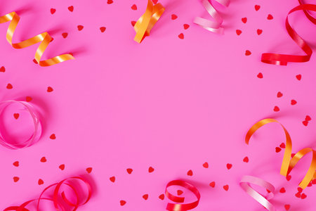 Bright festive pink background with streamers and hearts confetti, copy spaceの写真素材