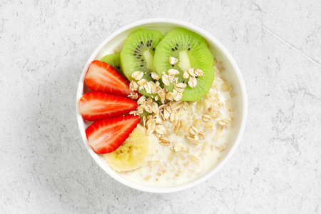 Oatmeal porridge bowl on the white table, healthy and nutritious breakfast, top viewの写真素材