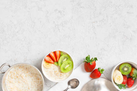 Background with oatmeal porridge and fresh fruits on the white table, healthy and nutritious breakfast, top viewの写真素材