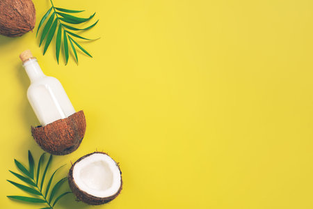 Bright yellow tropical background with coconut milk and palm leaves, copy spaceの写真素材