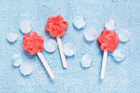 Popslices of fresh watermelon and ice on the blue background, top viewの写真素材