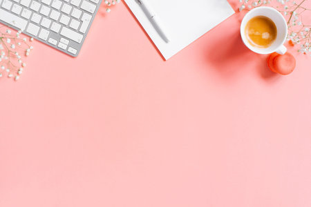 Tender light pink background with morning coffee, notepad and keyboard, copy space