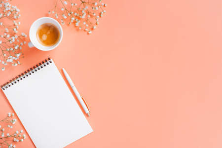 Tender light peach background with opened notepad and cup of coffee, copy spaceの写真素材