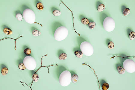 Pattern of chicken and quail easter eggs and branches on the green background, top viewの写真素材