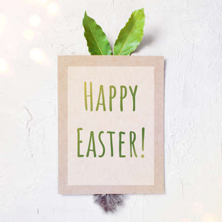 The blank poster with bunny ears and tail with text Happy Easter on the white textured table, copy spaceの写真素材