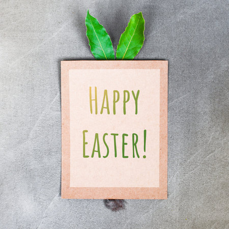 Poster with bunny ears and tail with text Happy Easter on the grey concrete table, concept, copy...