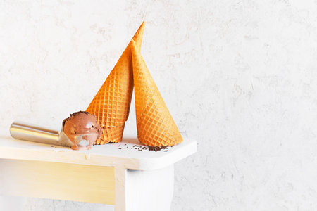 Waffles cones and ice cream ball in the metal spoon on the white background, copy space