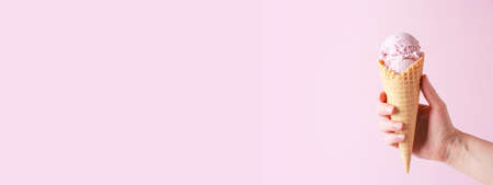 Pink banner with female hand holding the ice cream, copy spaceの写真素材