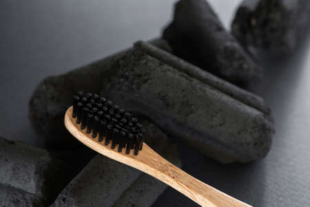 Bamboo toothbrush with charcoal bristles on the charcoal pieces, closeupの写真素材