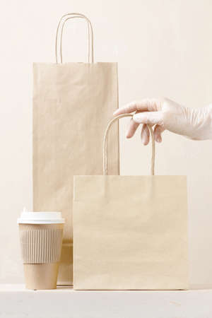 Concept of safe delivery in the period of pandemic. Gloved hand holding the paper bag.の写真素材