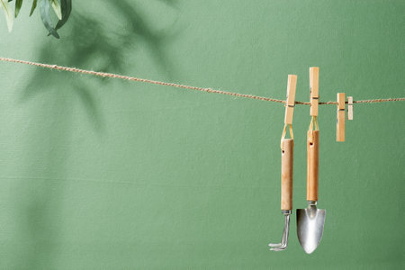 Gardening tools hanging on the rope, shovel and rake on the natural green background, conceptual backgroundの写真素材