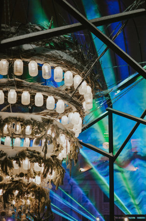 designer fir tree hanging in the air with garland in winter christmas town on advent with laser showの写真素材