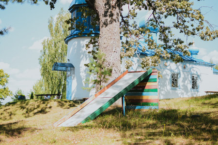 old Soviet wooden colored slide for children on the street against the backdrop of trees and churchの写真素材