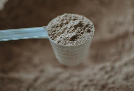 measuring cup with chocolate protein for training athlete
