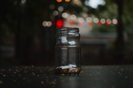 ashtray from a can with cigarette butts on a table with a rear view of a courtyard with lights