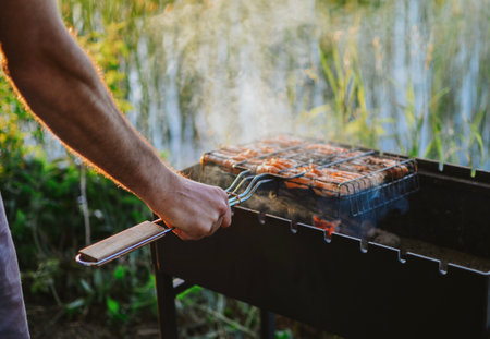 cooking juicy fish with smoke on a grill in nature on a lake in summerの写真素材