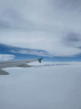view from airplane window with sunny sky and clouds during flight on vacation