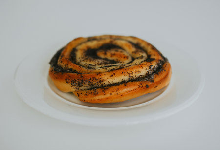 delicious bun with poppy seeds just out of the oven on a plate in a cafe on a white backgroundの写真素材