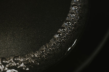 boiling water with macro bubbles close-up on black kitchen stove for cookingの写真素材