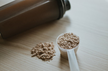 measuring cup with chocolate protein and a shake next to it for making a shake for athletesの写真素材