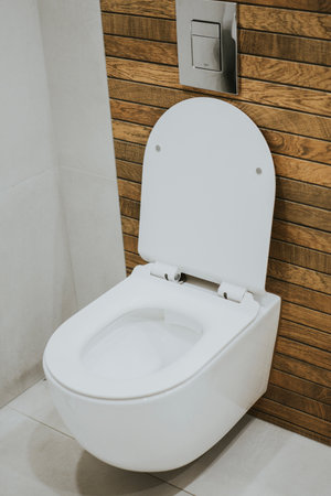 white new toilet mounted on the wall against a background of stylish wood tiles and neutral greyの写真素材