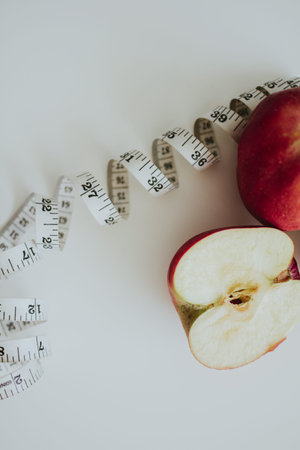 measuring tape for body and on the white background with red bright apples for health