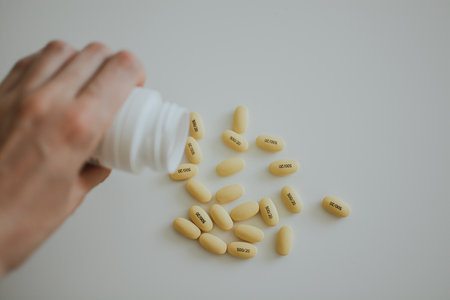 woman pours yellow pills from a jar on a white backgroundの写真素材