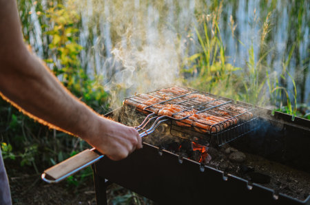 cooking juicy fish with smoke on a grill in nature on a lake in summer in Estoniaの写真素材
