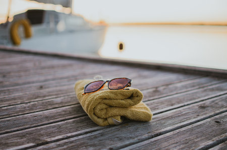 bathing towel, sunglasses, hair clip against the backdrop of a lake on an evening sunny day for swimmingの写真素材