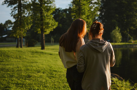 mother and daughter walk together next to the lake and talk in nature in the summerの写真素材