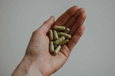 woman holding green pills in her hand with white backgroundの写真素材