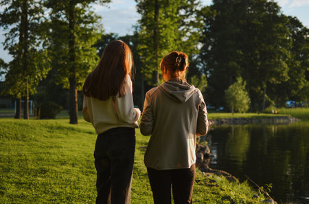 mother and daughter walk together and talk in nature in the summer on a sunny eveningの写真素材
