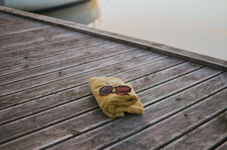 bathing towel, sunglasses and slippers against the backdrop of a lake on an evening sunny day for swimmingの写真素材
