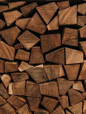 Stacked firewood of different shapes from forest trees for sale