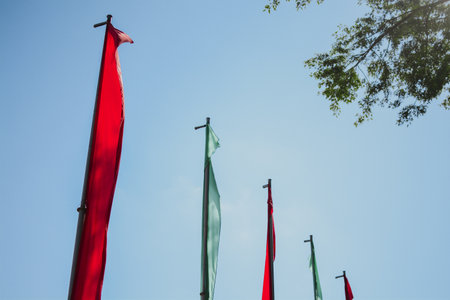 red and green flags hanging on a pole in the sky on a square in the cityの写真素材