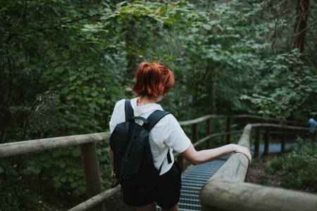 hiker goes down the stairs with railings in the depths of the forestの写真素材