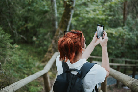 a traveler goes down the stairs and takes a photo on her phone in the depths of the forestの写真素材