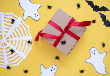 halloween gift box with ghosts, spiders, cobwebs, bats on an yellow background for celebrating