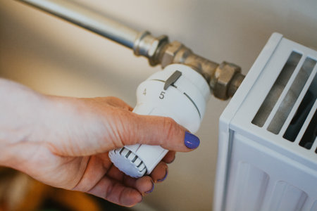 A womans hand turns the handle of the radiator heating for heating in the apartment and houseの写真素材