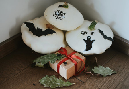 many small white pumpkins with a pattern of a cobweb, ghost, bat, spider and a gift for Halloween