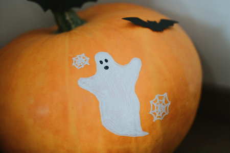 huge orange pumpkin with a pattern of a white ghost, a web and a bat for the holiday of Halloweenの写真素材