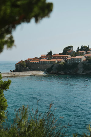 view from a private beach with rocks and the sea to the touristic ancient Sveti Stefan in Montenegroの写真素材